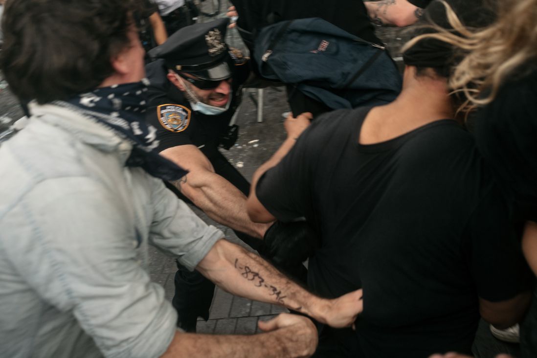 An NYPD officer struggles with protesters outside Barclays Center.